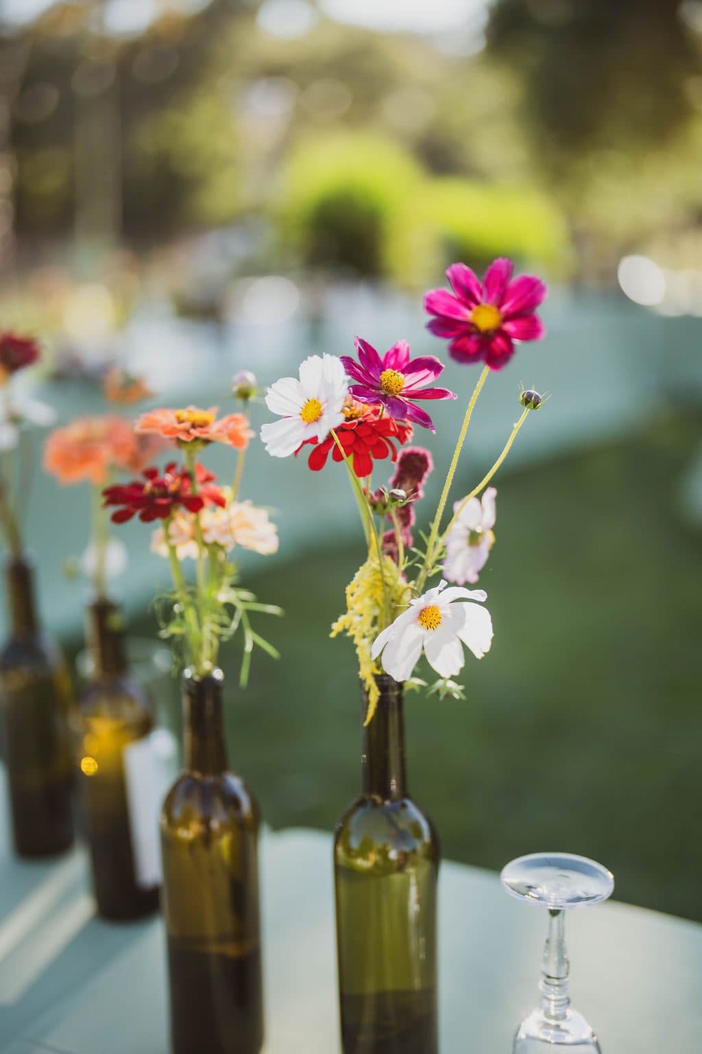 Wine-bottle bud vases lined with garden flowers along the reception tables