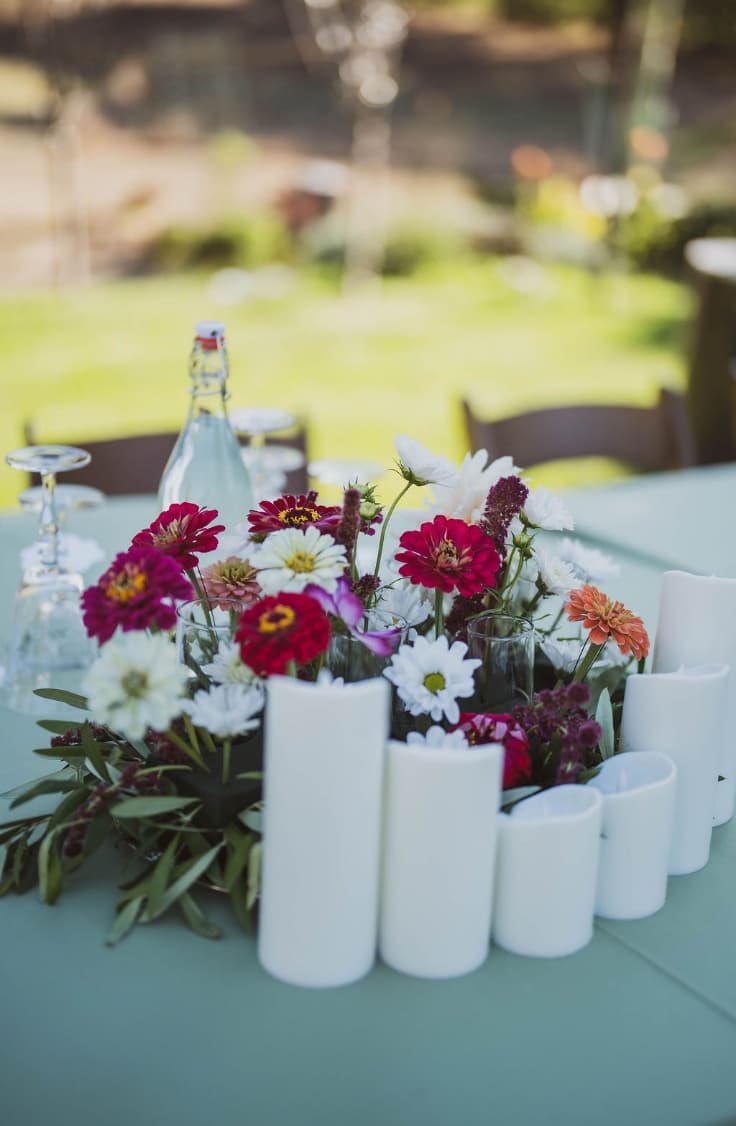 Homegrown zinnia and cosmos centerpiece with white pillar candles